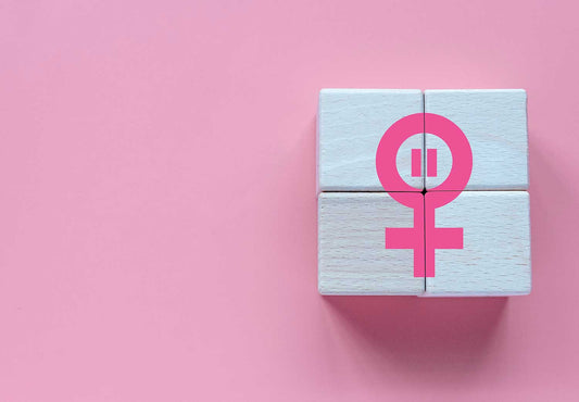 Caja blanca con símbolo femenino rosa sobre un fondo rosa pastel. Representación de la salud femenina, el empoderamiento y la conciencia sobre la menopausia y la premenopausia
