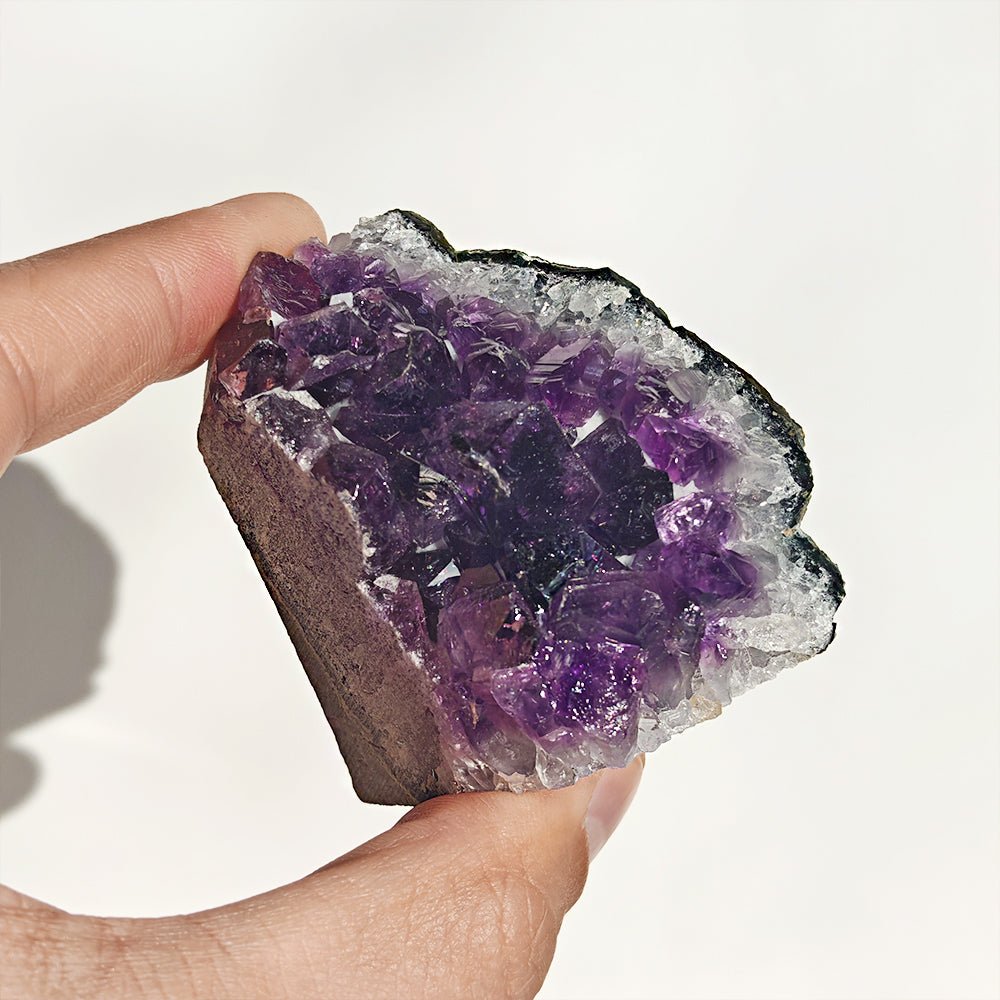Drusa de amatista con base plana de cristal púrpura, muestra detalles de cristales y estructura natural en imagen.