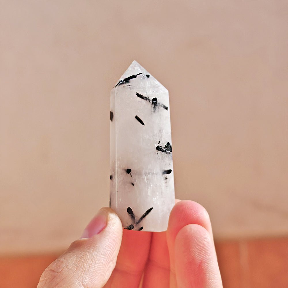 Punta de cuarzo turmalinado de Mystical Tienda, cristal con bandas negras y rosadas, forma puntiaguda y brillante.