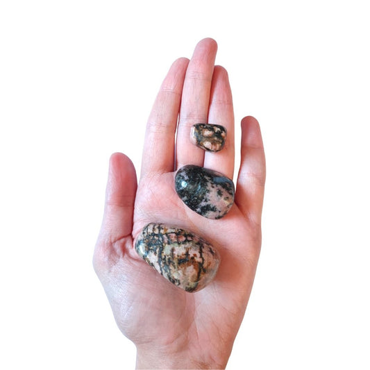 Rodado de rodonita de la marca Mystical Tienda, mostrando su superficie rosada y detalles naturales en una imagen cercana.