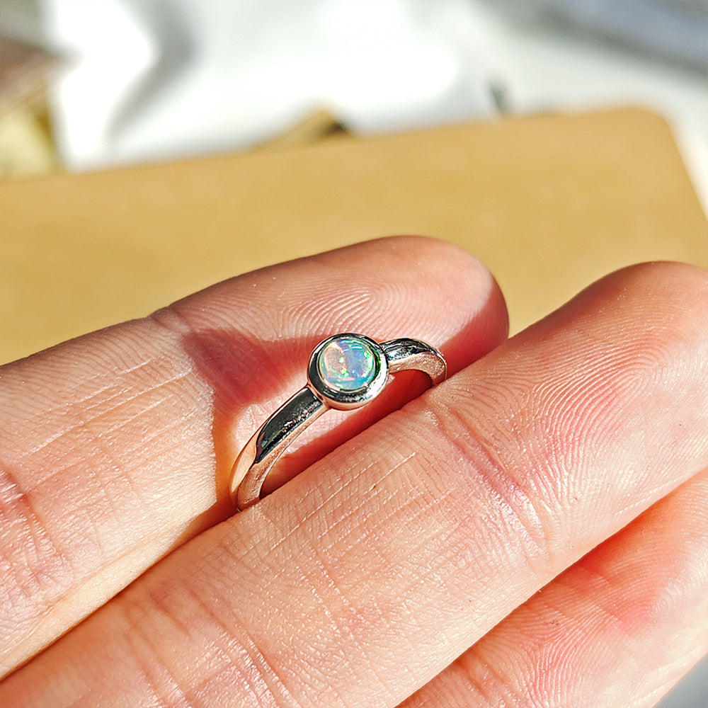 Anillo de plata de ley 925 con círculo de ópalo en un diseño elegante y delicado sobre fondo neutro.