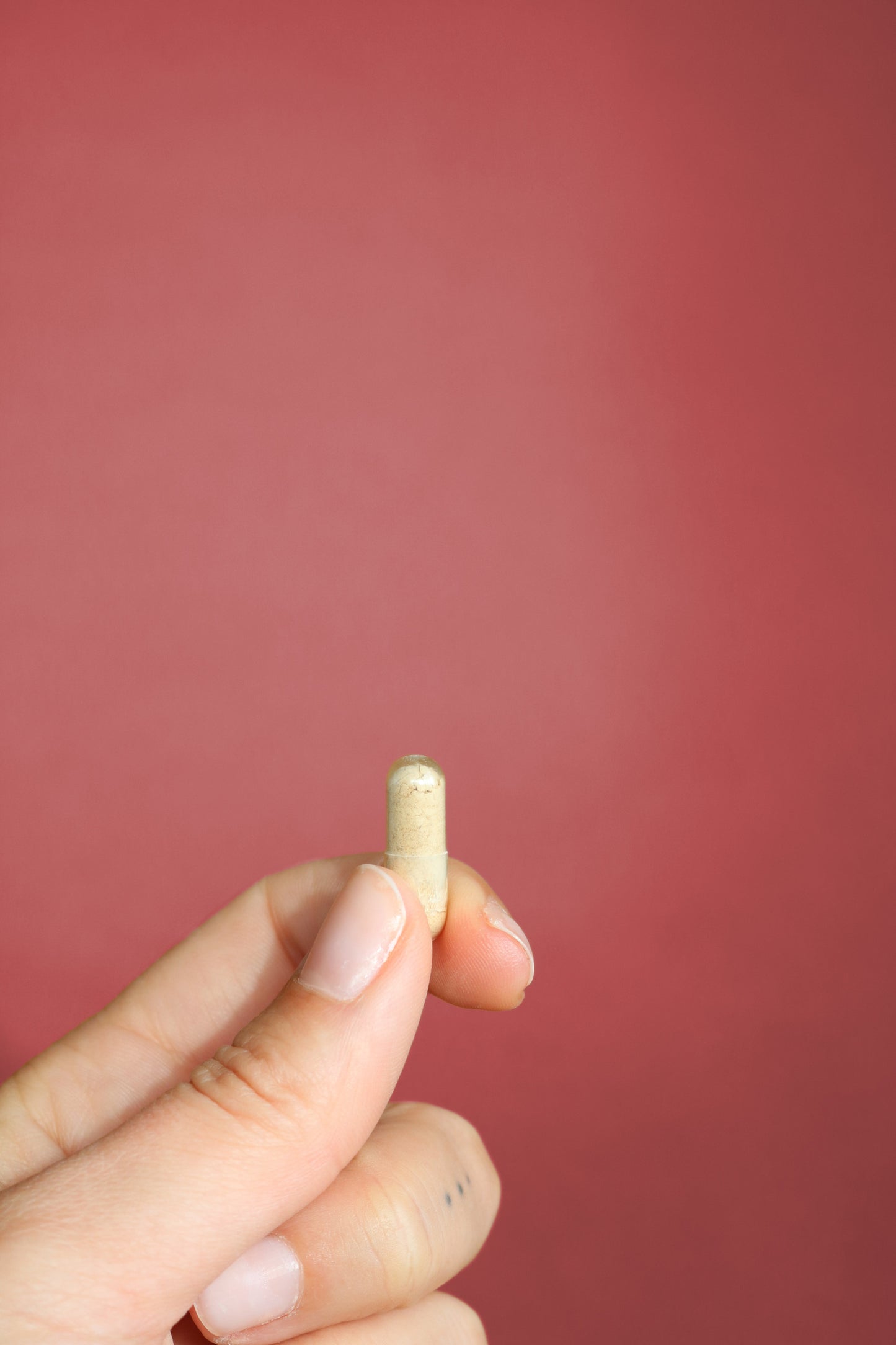 Capsula de FemmeUp Detox en mano, fondo rosa, muestra el envase de cápsulas para detoxificación femenina.