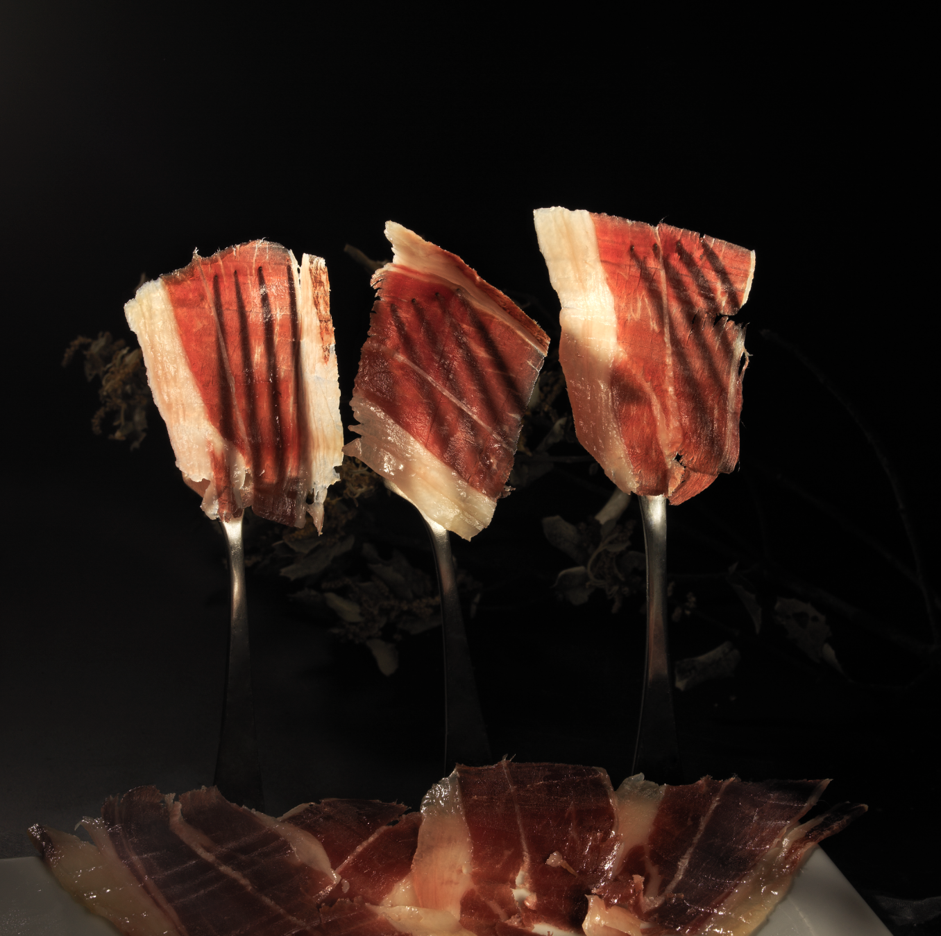 Jamón de Bellota 100% Ibérico MONJAMON Y MAS en lonchas finas, con textura y color característicos del jamón ibérico de alta calidad.