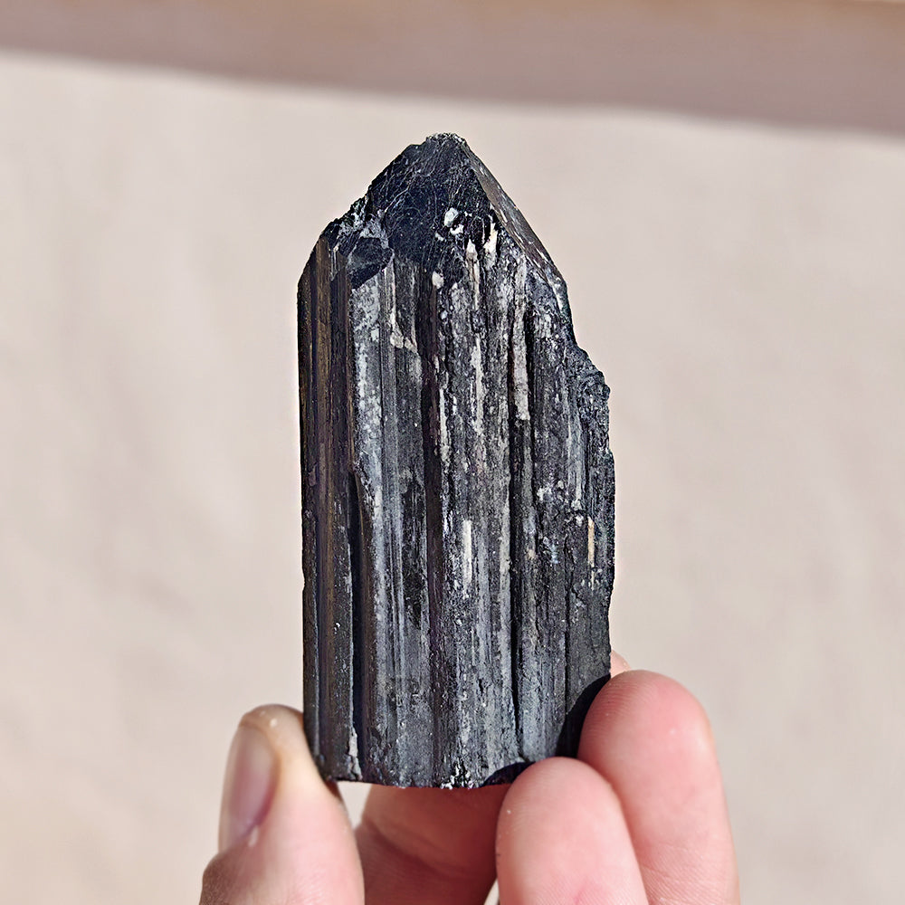 Punta de turmalina negra semipulida de Mystical Tienda, muestra la textura y forma de la piedra natural para terapias y decoración.