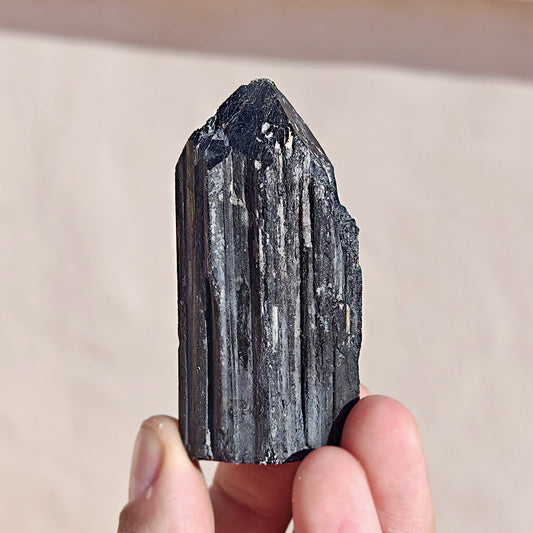 Punta de turmalina negra semipulida de Mystical Tienda, muestra la textura y forma de la piedra natural para terapias y decoración.