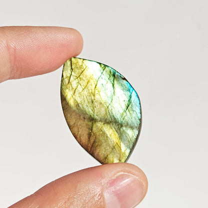 Cabujón rodado de labradorita de Mystical Tienda, muestra reflejos azules y verdes en su superficie brillante y ovalada.