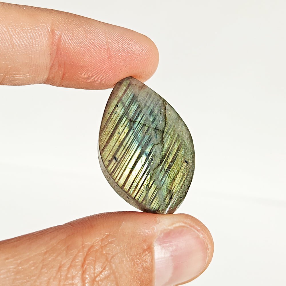 Cabujón de Labradorita en forma rodado, piedra con destellos azules y verdes, de la marca Mystical Tienda, sobre fondo neutro.