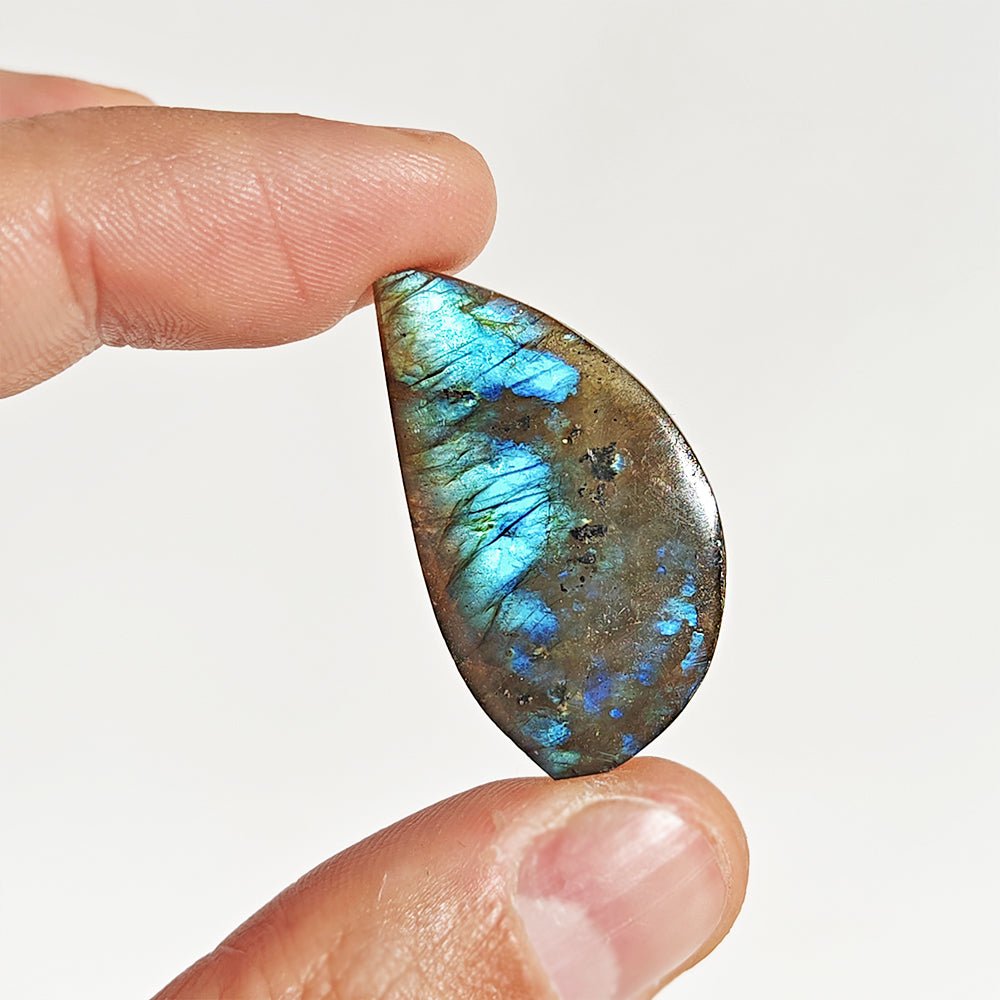 Cabujón de labradorita en forma rodado, brillante y con reflejos azules y verdes, de la marca Mystical Tienda.