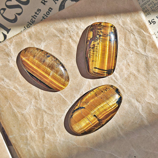 Cabujón plano de Ojo de Tigre de la marca Mystical Tienda, mostrando su brillo dorado y patrones naturales en la piedra.