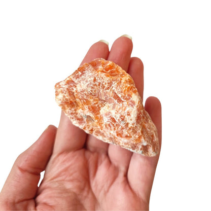 Cristal de calcita naranja en bruto, mineral natural de color vibrante, muestra textura y forma irregular, de Mystical Tienda.