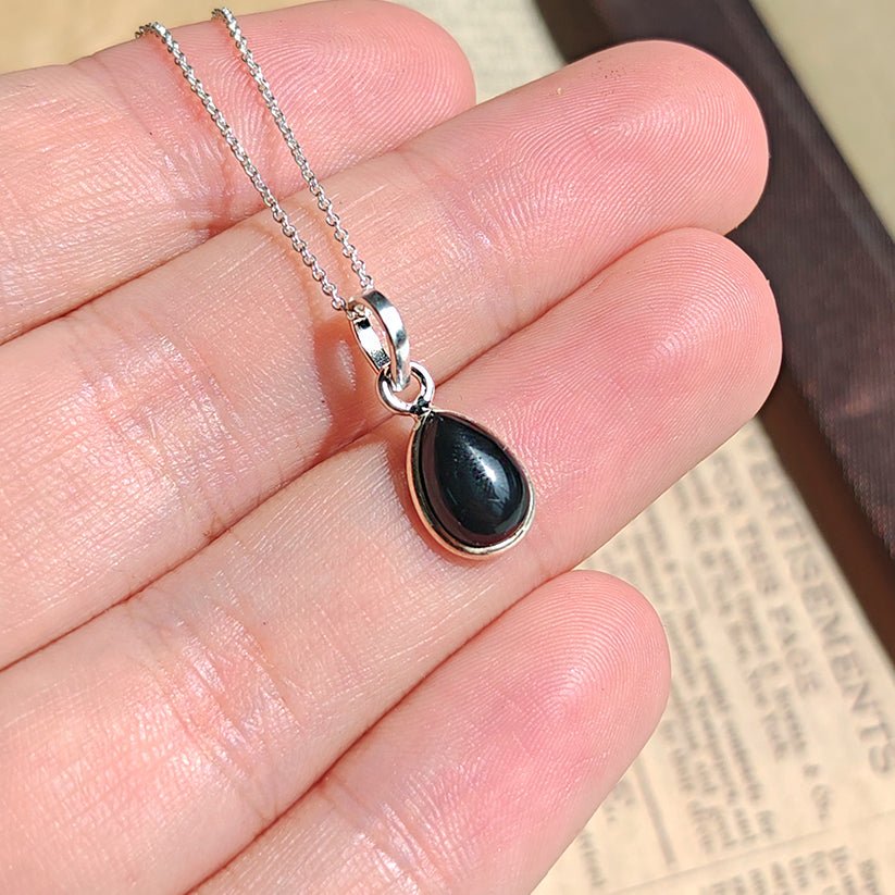 Colgante de plata con ónix y diseño elegante, llamado Aurora, de la marca Mystical Tienda, en un fondo neutro.