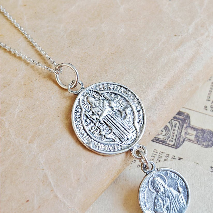 Colgante doble protección con San Benito y San Judas Tadeo en plata de ley 925, símbolo de fe y protección.