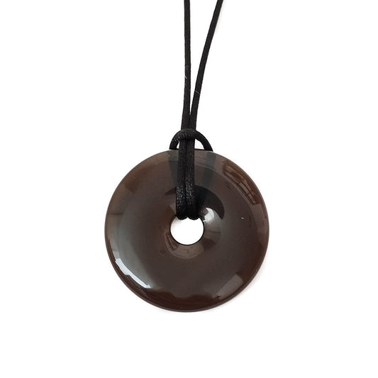 Colgante Donut de Cuarzo Ahumado, mineral natural en forma de donut, con detalles en tonos oscuros y brillo suave.