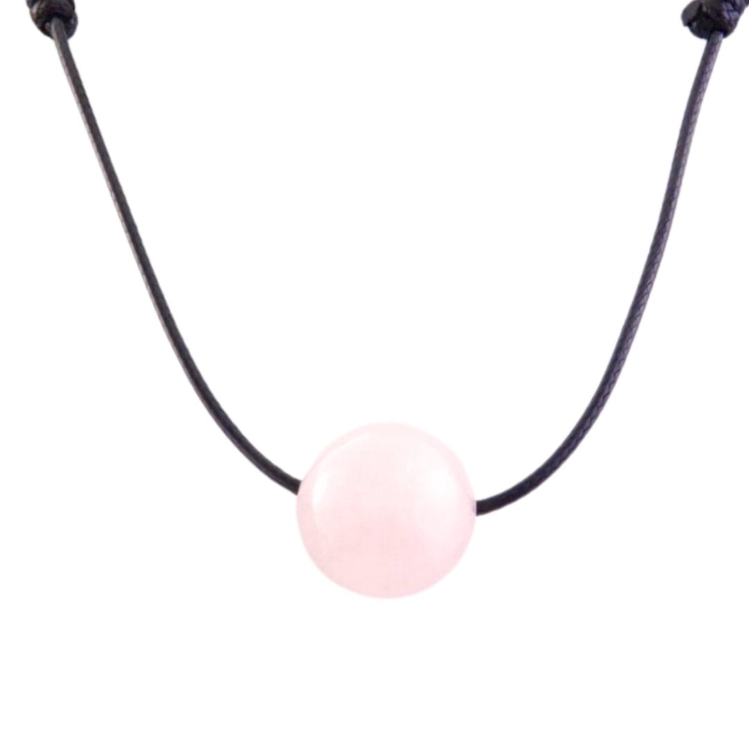Colgante de mineral esfera de cuarzo rosa, pieza decorativa y espiritual, con cordón en un fondo neutro.