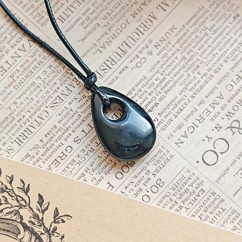Colgante lágrima agujereada de ónix, mineral negro con acabado pulido, diseñado por Mystical Tienda para joyería bohemia.