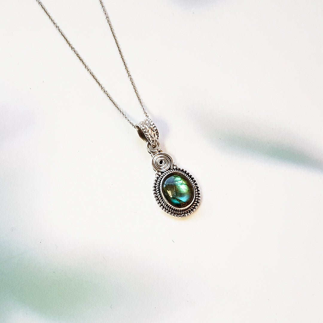 Colgante oval de labradorita y plata de ley 925, joya de estilo elegante y natural, con detalles en plata en la imagen.