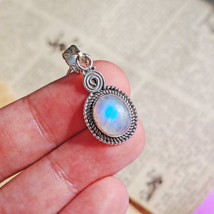 Colgante de plata de ley 925 con espiral y piedra de luna en forma ovalada, diseño elegante y natural.