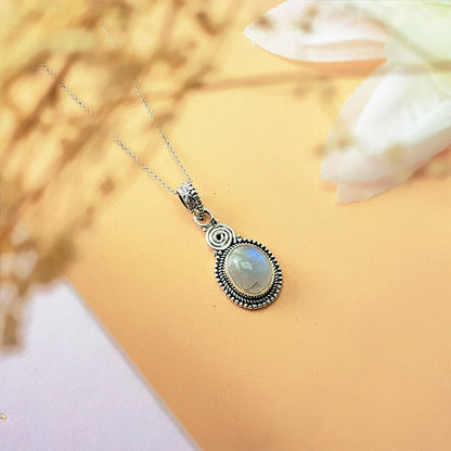 Colgante de plata de ley 925 con espiral y piedra de luna en forma ovalada, diseño elegante y místico.