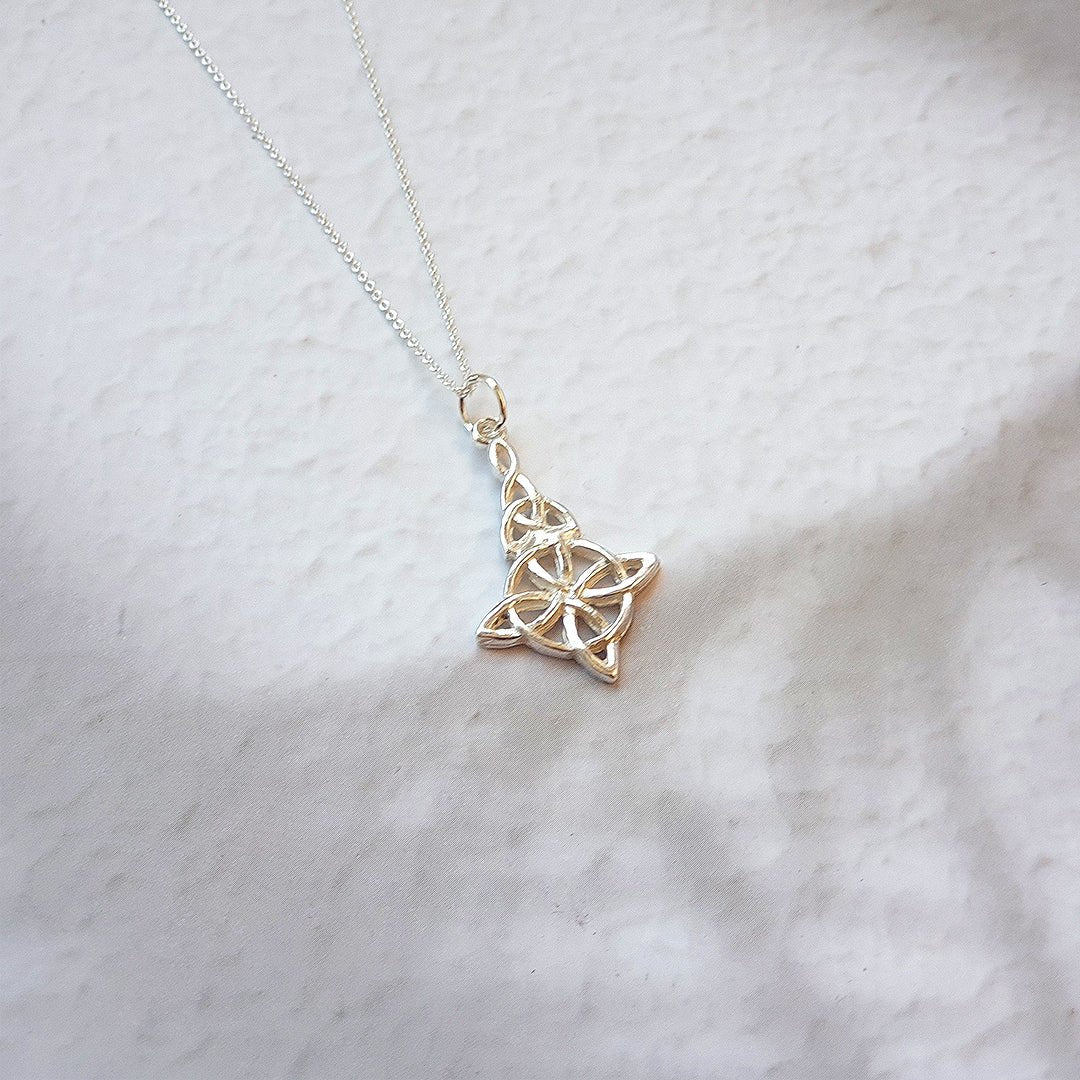 Colgante largo de plata de ley 925 con nudo de bruja y triqueta, diseñado por Mystical Tienda, en un fondo neutro