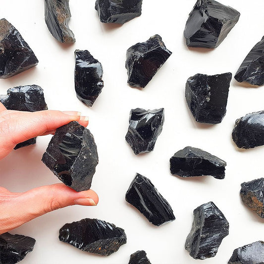 Piedra de obsidiana en bruto de Mystical Tienda, muestra textura natural y forma irregular en un fondo neutro.