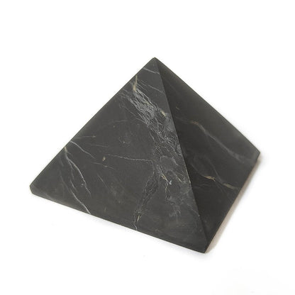 Pirámide de shungit de Mystical Tienda, muestra la forma piramidal y la textura negra del mineral shungit sobre fondo neutro.