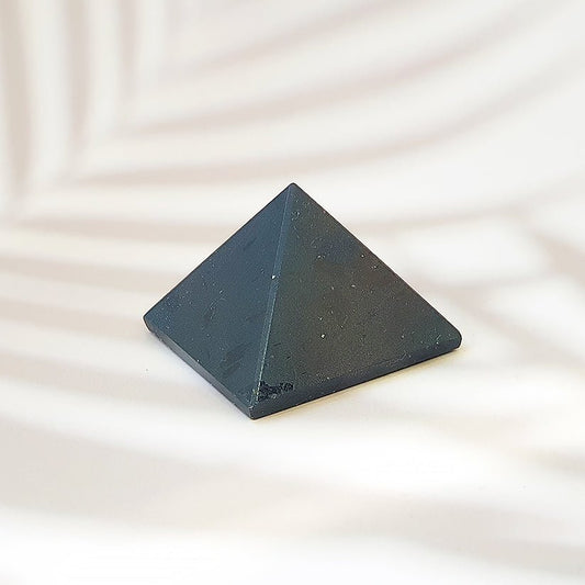Figura geométrica de pirámide de turmalina negra de Mystical Tienda sobre fondo neutro.
