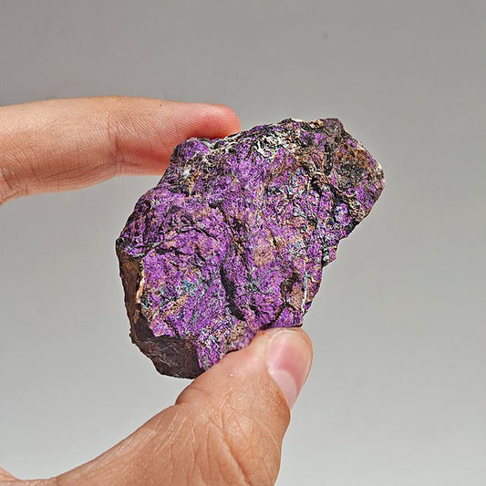 Cristal de purpurita en bruto, mineral natural sin pulir, de la tienda Mystical, con formas y texturas irregulares visibles.