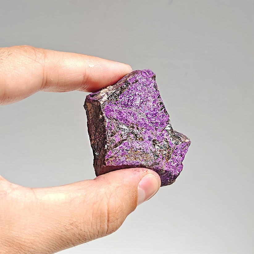 Cristal de purpurita en bruto, mineral natural sin pulir, de la marca Mystical Tienda, con forma irregular y superficie cristalina.