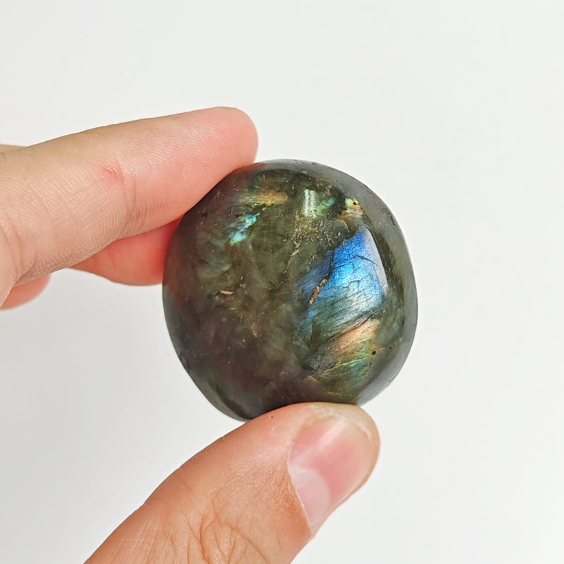 Rodado palm stone de labradorita de Mystical Tienda, piedra pulida y redonda con reflejos irisados en tonos azules y verdes.