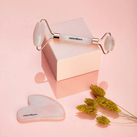 Rodillo facial de cuarzo rosa y Gua Sha de innovagizmo, mostrando el rodillo y la piedra Gua Sha en uso en la piel.