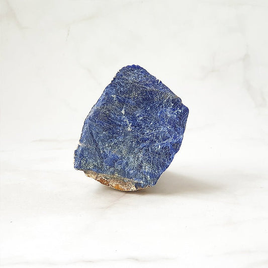 Muestra de sodalita en bruto, mineral natural sin pulir, en tonos azules y grisáceos, de la tienda mística Mystical Tienda.