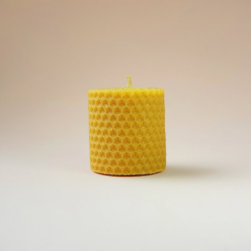 Vela de miel de la marca Mystical Tienda, con cera en color dorado y mecha de algodón, en un recipiente decorativo.