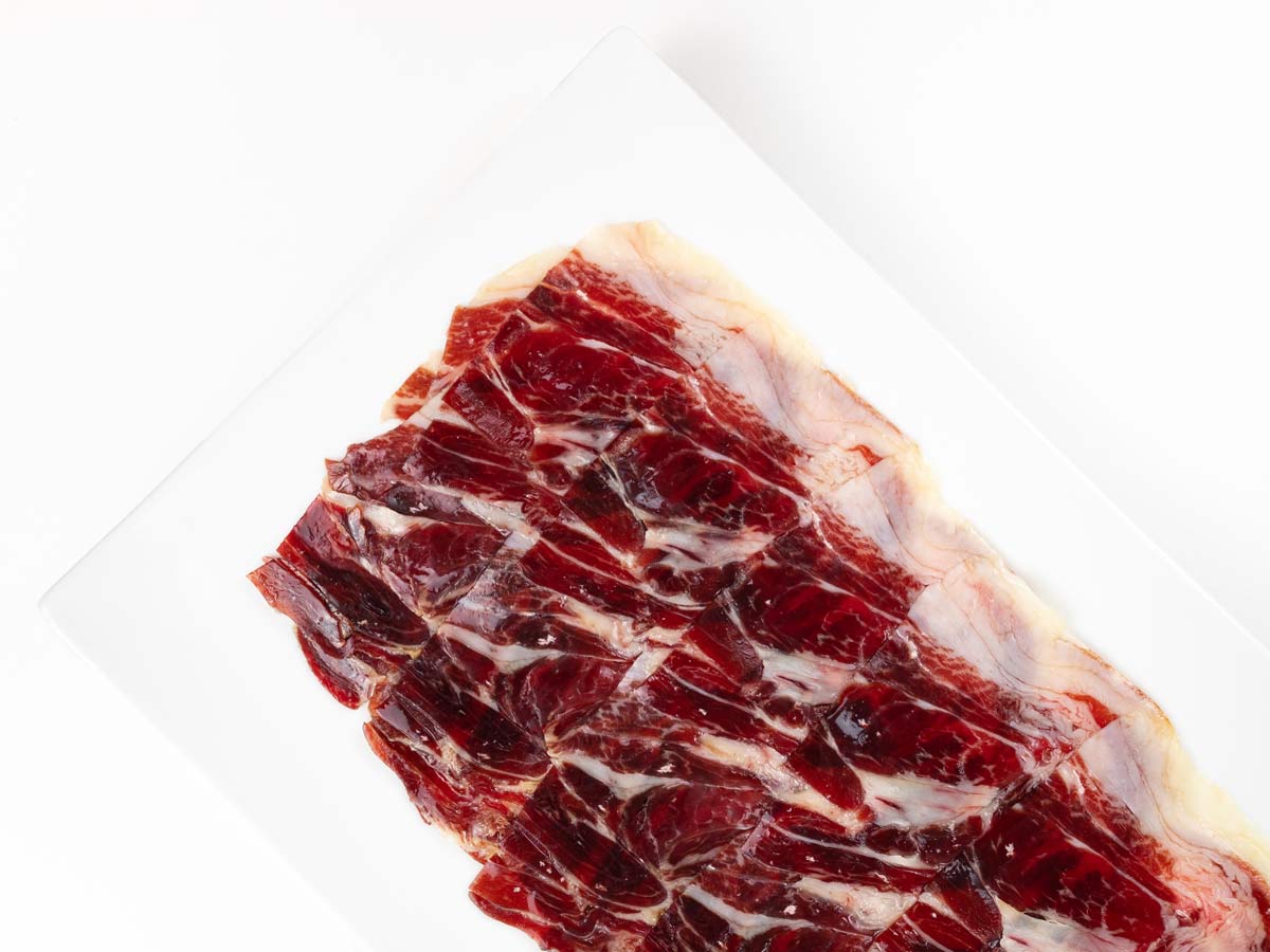 Jamon ibérico de bellota Sagrada Paleta 80g de la marca Monjamón y Más, vista en detalle con cuchillo.